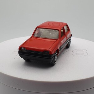 May include: A red toy car with black detailing and the words "SAPEURS POMPIERS" printed on the side. The car is a model of a French fire truck.