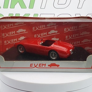 May include: A red die-cast model car in a display box. The car is a classic roadster with a sleek design and silver wheels. The box has the word "EVEM" repeated on a red background.