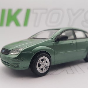 May include: A green diecast model car of a Ford Focus. The car has black wheels and a detailed interior.