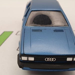 May include: A blue toy car model of an Audi 80, a classic compact car from the 1970s and 1980s.