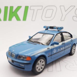 Può includere: Un'auto della polizia giocattolo blu e bianca con una barra luminosa sulla parte superiore. L'auto ha la scritta "POLIZIA" sul lato.