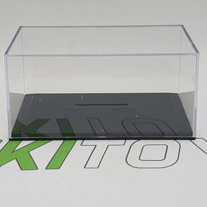 Può includere: Una teca espositiva in acrilico trasparente con una base nera. La teca è vuota e ha una forma rettangolare.