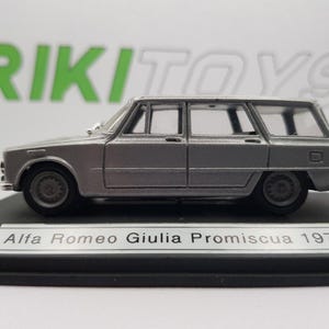 Może przedstawiać: Srebrny model samochodu Alfa Romeo Giulia Promiscua 1972 w gablocie. Samochód to kombi z czarnym wnętrzem.