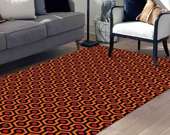 Può includere: Tappeto a motivi arancioni e neri con un design geometrico. Il tappeto presenta un motivo ripetitivo di esagoni con accenti rossi.