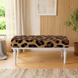 May include: A rectangular bench featuring a brown and black leopard print upholstered seat supported by four white turned wooden legs. The bench has a low profile and a flat top surface, providing a clear view of the animal pattern fabric.