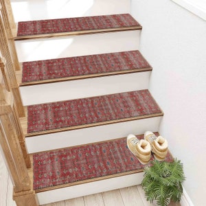 May include: Red patterned stair treads with a distressed look, covering a set of wooden stairs. The treads are made of a soft, non-slip material and are perfect for adding a touch of style and safety to your home.