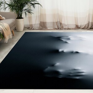 Puede incluir: Alfombra de área abstracta con un fondo azul oscuro y un diseño blanco, borroso y texturizado. El diseño se asemeja a una serie de manos superpuestas.