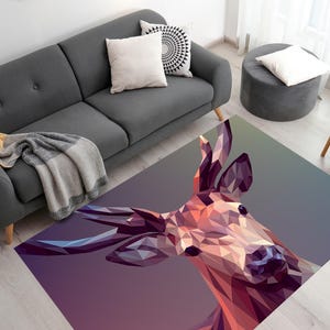 May include: Geometric deer head rug in shades of purple, pink, and brown. The rug is rectangular and features a low-poly design. The rug is placed on a light wood floor in a living room setting.