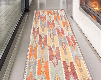 May include: A rectangular, patterned rug with a geometric design in shades of orange, red, gray, and yellow. The rug is placed on a polished concrete floor, adding a touch of warmth and color to the space. The rug's design features repeating diamond and geometric shapes.