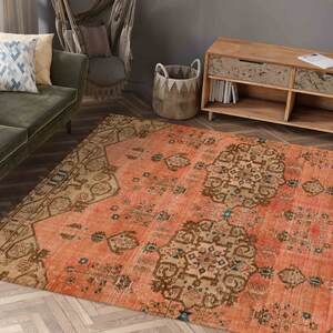 May include: A vintage-style rug with a peach background and intricate brown and blue patterns. The rug has a distressed look and is perfect for adding a touch of bohemian style to any room.