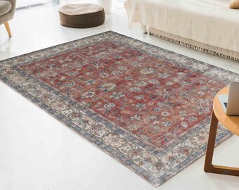 May include: A red, beige, and blue patterned rug with a floral design. The rug has a distressed look and is laid out on a white floor.