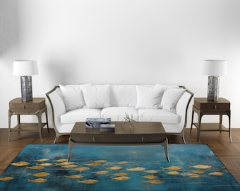 Puede incluir: Un sofá blanco con dos mesas auxiliares y lámparas, una mesa de centro con un objeto decorativo y una alfombra azul con un patrón de peces dorados.