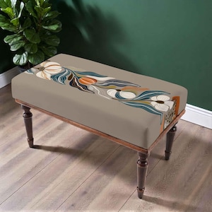 May include: A rectangular bench with four dark brown wooden legs and a beige upholstered seat. The top of the seat features a horizontal graphic print of stylised white flowers with dark blue and orange leaves arranged in a continuous pattern.