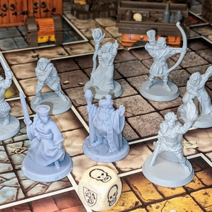 Puede incluir: Un juego de mesa con un dado gris en forma de calavera y ocho figuras de plástico gris sobre un tablero de baldosas marrones y grises. Las figuras están en varias poses e incluyen un mago, un guerrero y un pícaro.