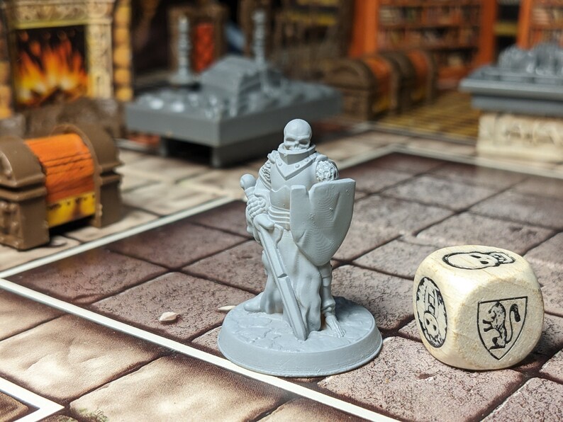May include: A gray plastic miniature of a skeletal knight holding a sword and shield, standing on a gray base. A wooden dice with a skull and a lion crest is in the foreground.