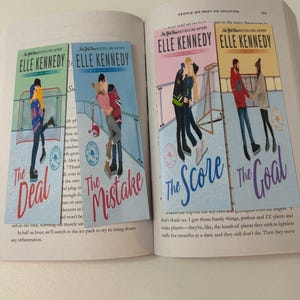May include: Four rectangular paper bookmarks featuring illustrations of couples on ice, titled The Deal, The Mistake, The Score, and The Goal by Elle Kennedy. Each bookmark displays a unique color scheme and scene, resting on an open book page.