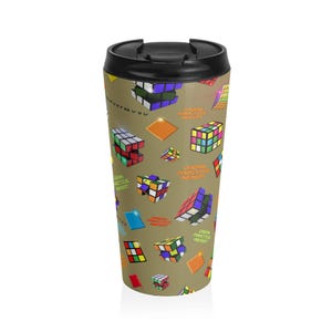 May include: A travel mug with a black lid and a tan body. The body is covered in colorful Rubik's Cube graphics and the words "Dream Practice Repeat". The mug is designed for hot or cold beverages.