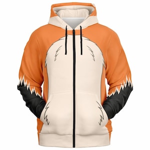Peut inclure: Sweat à capuche zippé orange et blanc avec un motif de renard. Le sweat à capuche présente une poitrine blanche, des manches et une capuche orange, des accents noirs sur les manches et une fermeture éclair noire.