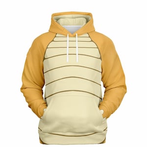 Op de afbeelding: Een gele en beige hoodie met een schubbenpatroon op de voorkant en mouwen. De hoodie heeft een capuchon met trekkoord en een kangoeroezak.
