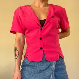 May include: A hot pink short-sleeved button-up blouse with a v-neck and a denim skirt.