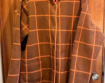 May include: Brown jacket with an orange plaid pattern. The jacket has a mandarin collar, two front pockets, and is buttoned up. The trim and lining are orange.