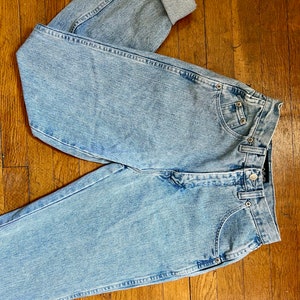 May include: Light blue denim jeans with a cuffed leg. The jeans have a high waist and a straight leg.
