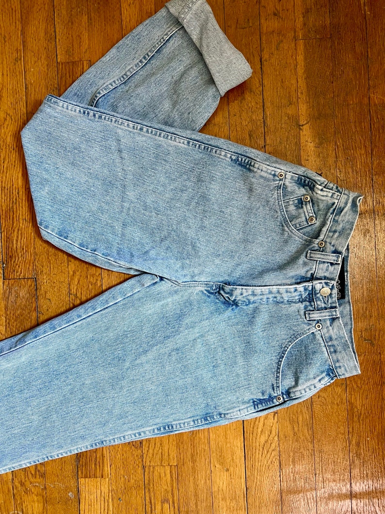 May include: Light blue denim jeans with a cuffed leg. The jeans have a high waist and a straight leg.
