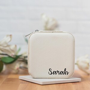 May include: White jewelry box with a zipper closure and the name "Sarah" printed on the front.