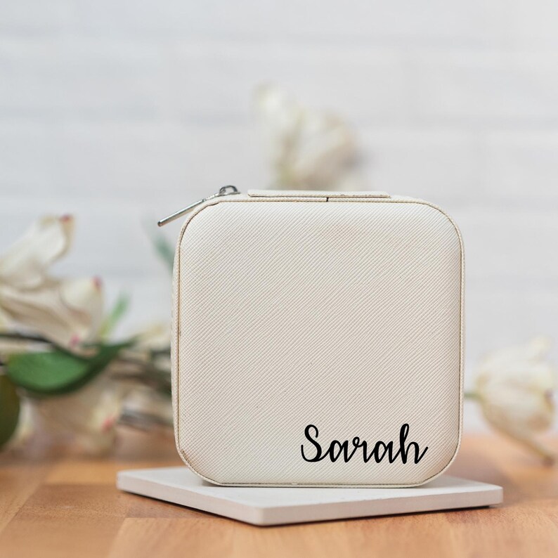 May include: White jewelry box with a zipper closure and the name "Sarah" printed on the front.