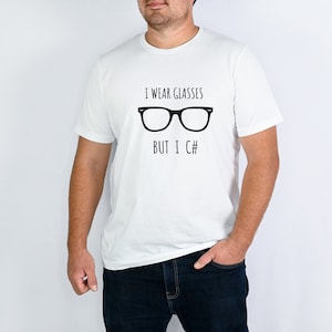 Pode incluir: Camiseta branca com o texto preto "I wear glasses but I C#" e um desenho de óculos pretos. Uma peça de roupa casual.