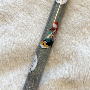 May include: A silver glitter pen with a black tip and a white sticker featuring a cartoon character and the text "Worm's Wort".