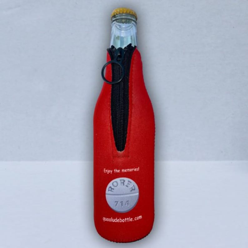 May include: A red bottle koozie with a black zipper and a black ring pull. The koozie has the text "Enjoy the memories!" and a graphic of a pill with the text "RORER 714" and the website "quaaludebottle.com".