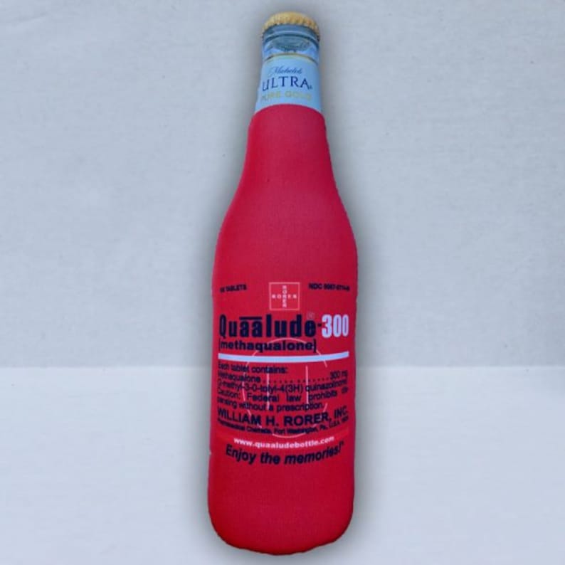 May include: A red bottle koozie with the text "Quaalude-300" and "Enjoy the memories!" printed on it. The koozie is wrapped around a clear glass bottle with a gold and blue cap.