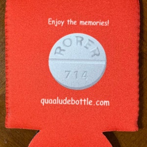 May include: A red beverage can cooler with a white pill graphic in the center. The pill has the word "RORER" and the number "714" printed on it. The text "Enjoy the memories!" and "quaaludebottle.com" are also printed on the cooler.