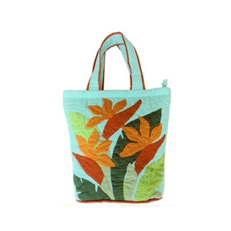 May include: A light blue tote bag with a floral design. The bag features orange and green appliqued flowers and leaves. The handles and trim are brown. The bag is made of quilted fabric.