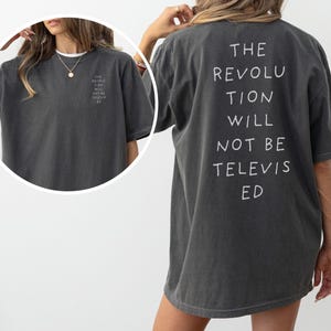 May include: A dark gray oversized t-shirt with the text "THE REVOLUTION WILL NOT BE TELEVISED" printed in white on the back.