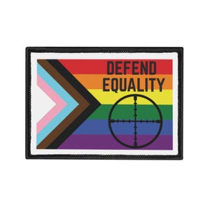 May include: Rectangular patch with a black border. The design features the Progress Pride flag with the words "DEFEND EQUALITY" in bold black letters. A black crosshair graphic is on the right side of the patch.