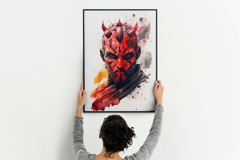 May include: A watercolour painting of Darth Maul, a character from the Star Wars franchise, with a red and black mask and horns. The painting is framed in black and is being hung on a white wall.