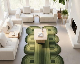 Può includere: Un soggiorno moderno con un tappeto verde geometrico. Il tappeto presenta un design curvo a strati in diverse tonalità di verde. Divani bianchi e un tavolino in legno chiaro completano l'estetica contemporanea. Il testo "ANYWAY CARPET" è visibile.