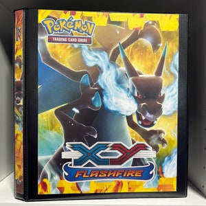 May include: A black binder with a Pokemon XY Flashfire trading card game design. The binder features a large image of a red and blue dragon with flames and the text "Pokemon Trading Card Game" and "XY Flashfire".
