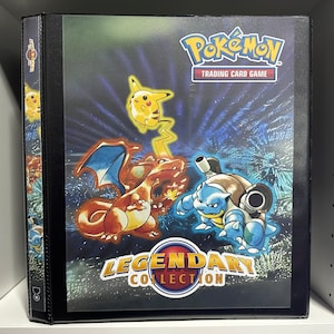 May include: A black binder with a blue, red, and yellow Pokemon Legendary Collection design. The binder features a Pikachu, Charizard, and Blastoise illustration. The text "Pokemon Trading Card Game" and "Legendary Collection" are printed on the binder.