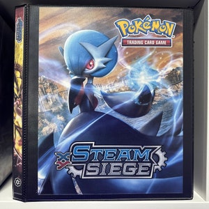 May include: A black binder with a blue and white Pokemon card game design. The binder features a large image of a blue and black Pokemon character with a blue and white background. The text "Pokemon Trading Card Game" and "Steam Siege" are visible on the binder.