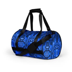 May include: A blue duffel bag with a repeating abstract design in shades of blue. The bag has black handles and a shoulder strap. The pattern appears to be a stylized representation of musical instruments. The bag is cylindrical in shape.