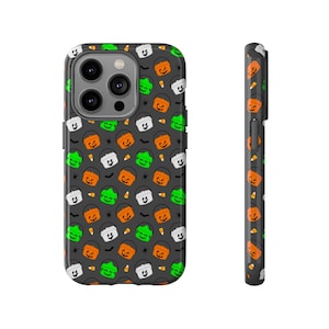 Puede incluir: Una funda de teléfono negra con un diseño de Halloween con cubos naranjas y verdes con caras sonrientes de calabaza.