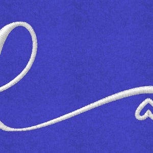 May include: White embroidered letter "e" with a heart detail on a blue background. The cursive letter is stylized with a loop and a flowing tail, ending in a small heart shape. The embroidery has a textured appearance.