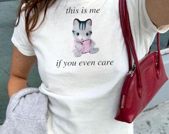 May include: White t-shirt with a cartoon cat wearing a pink dress and the text "this is me if you even care".