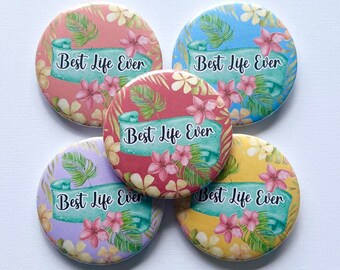 May include: Five round buttons with a tropical floral design and the text "Best Life Ever" in black lettering. The buttons are in various colors, including pink, blue, yellow, and green.