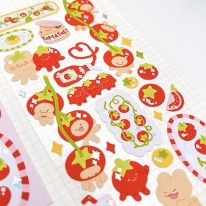 May include: A sheet of decorative stickers featuring various tomato-themed designs. The stickers include red tomatoes with green stems, tomato characters, and the word "Tomatoes". Some stickers have glitter accents.
