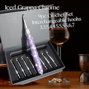 May include: A 9-piece interchangeable crochet hook set in a grey storage box. The set includes one handle with a purple, pearlescent, mosaic-patterned grip and eight silver-toned metal hook tips in sizes 3, 3.5, 4, 4.5, 5, 5.5, 6, and 7.