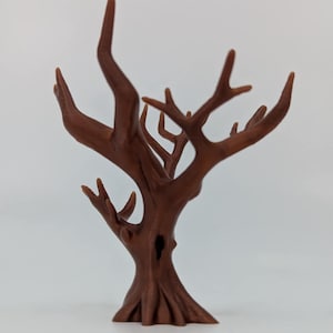 Puede incluir: Una escultura decorativa de árbol marrón con una superficie texturizada. El árbol tiene múltiples ramas y un tronco detallado. La escultura está hecha de un material sólido y se apoya sobre una base plana. El árbol es un objeto decorativo.